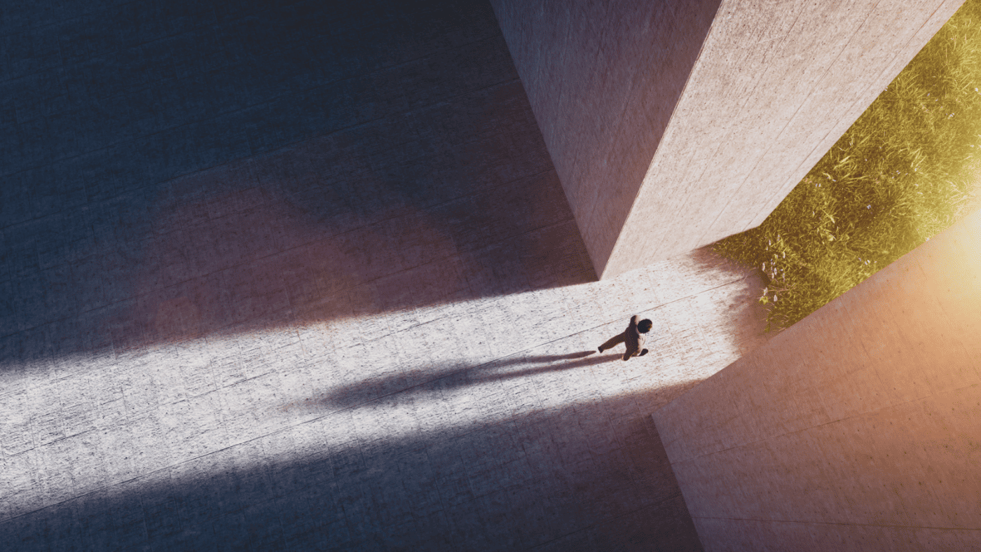 Business person walks from a grey office into a green field