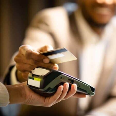 Man holding credit card over card machine.