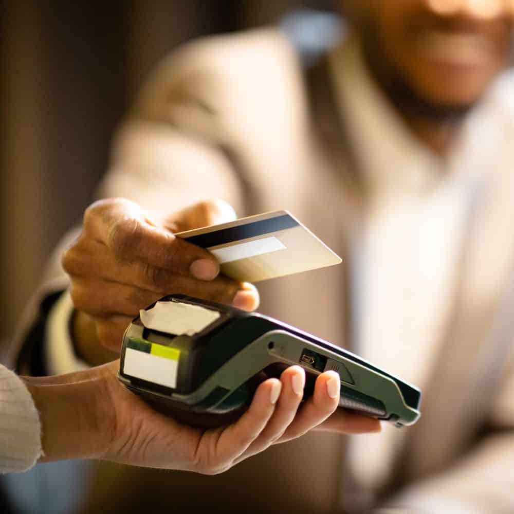 Man holding credit card over card machine.