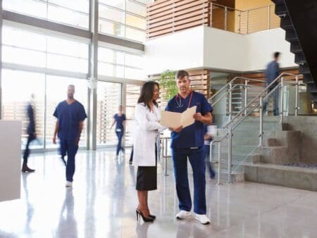 Healthcare professionals standing in lobby of hospital looking at documents.