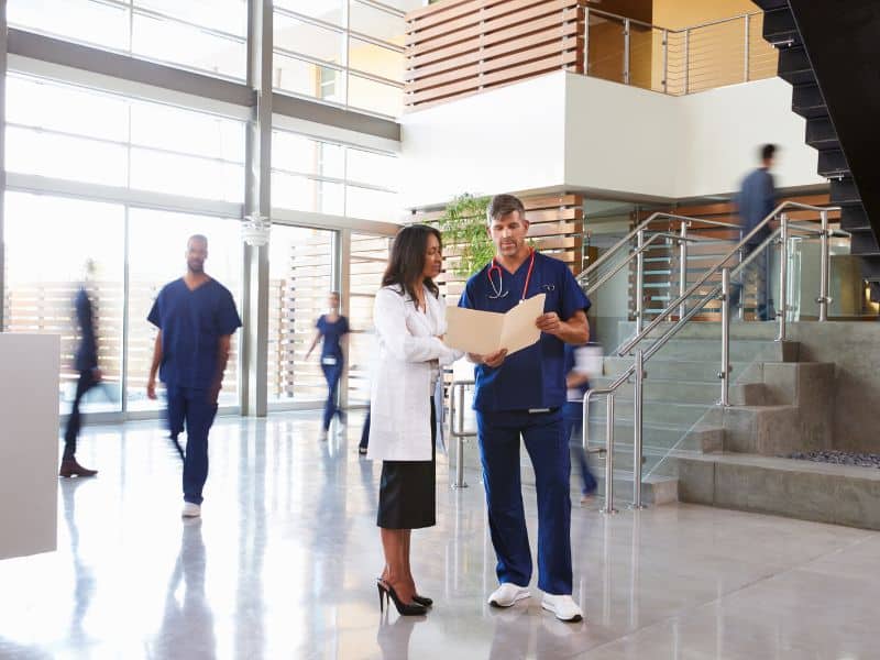 Healthcare professionals standing in lobby of hospital looking at documents.