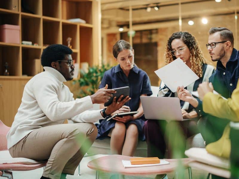 Group of people talking with laptop, tablet and notebooks.