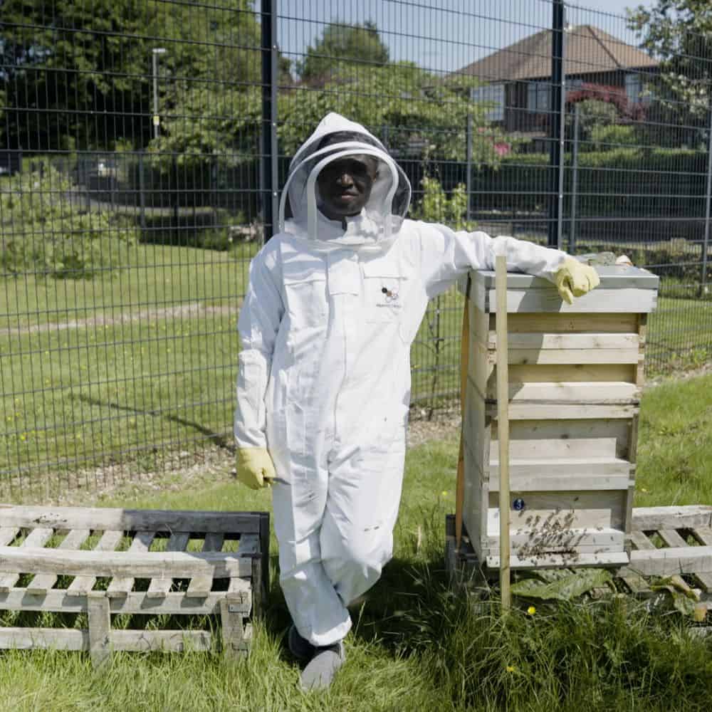 Oluwaseun outdoors, dressed in bee-keeping suit