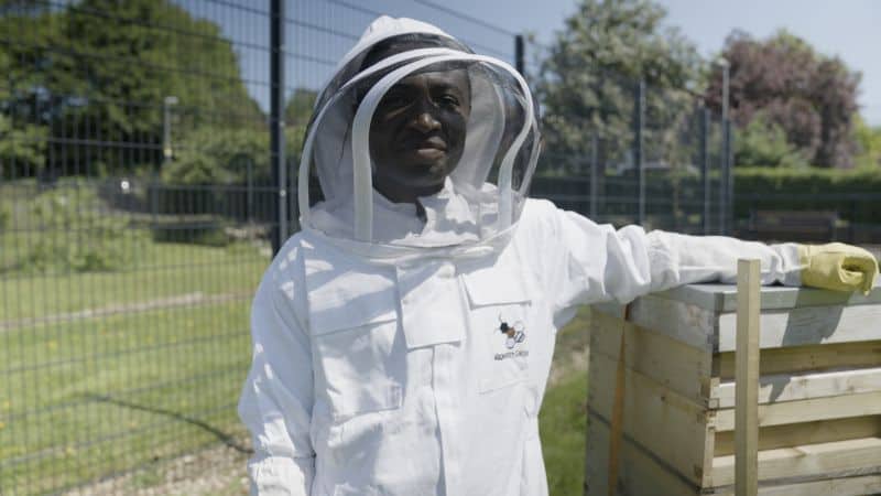 Oluwaseun outdoors, dressed in bee-keeping suit