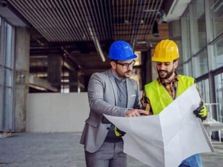A design engineer and construction worker look at plans onsite