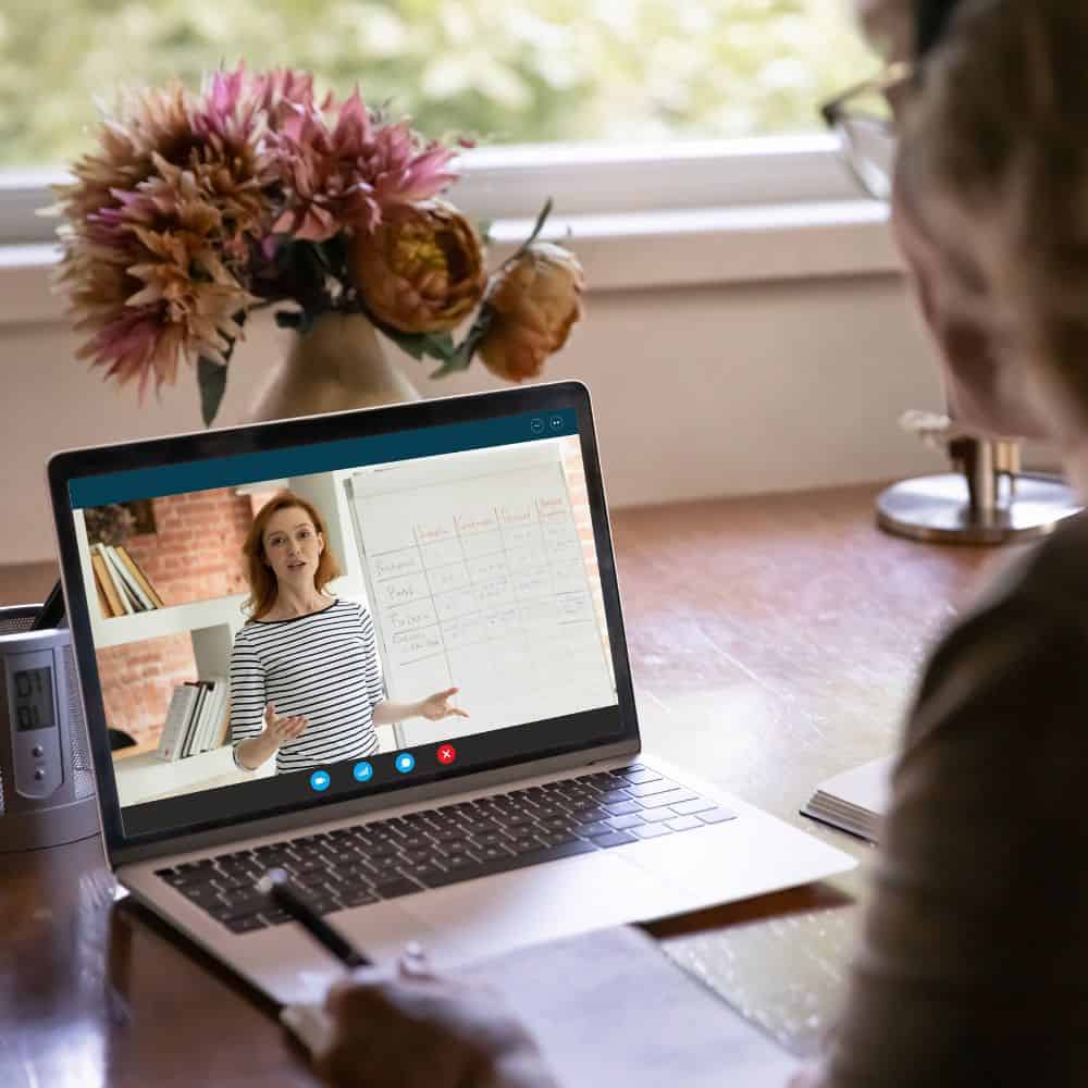 Image of woman watching laptop screen, which is a woman presenting an online session