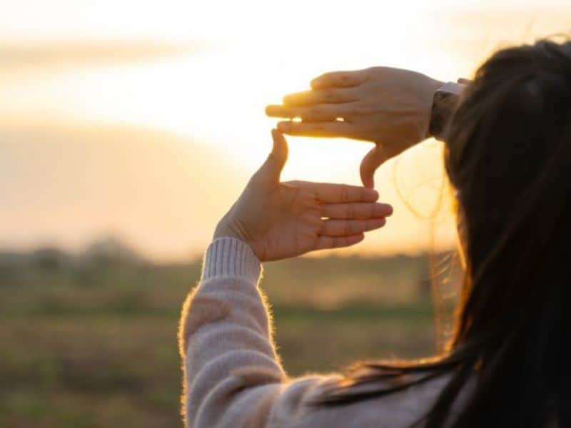 Woman creating a frame with her hands and looking into the distance outdoors