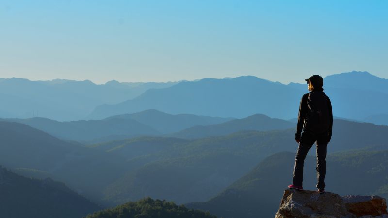 Person standing at the top of a mountain overlooking the landscape