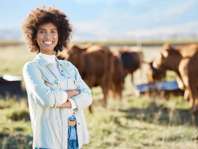 Woman stands in a field in front of cows