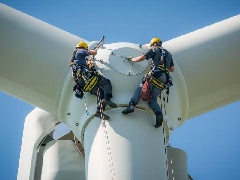 Two people work to install a wind turbine