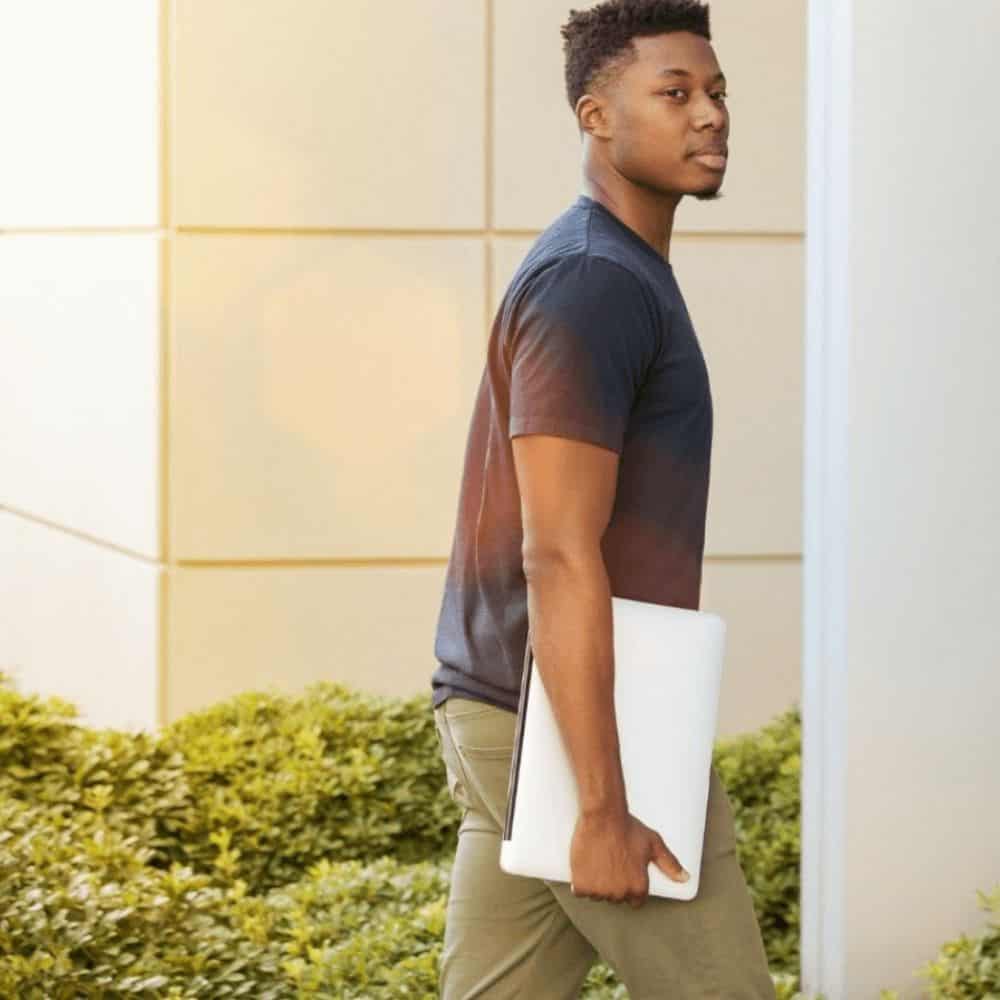 Image of man walking into a building holding a laptop