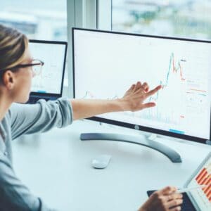 Woman pointing at computer screen with graphs