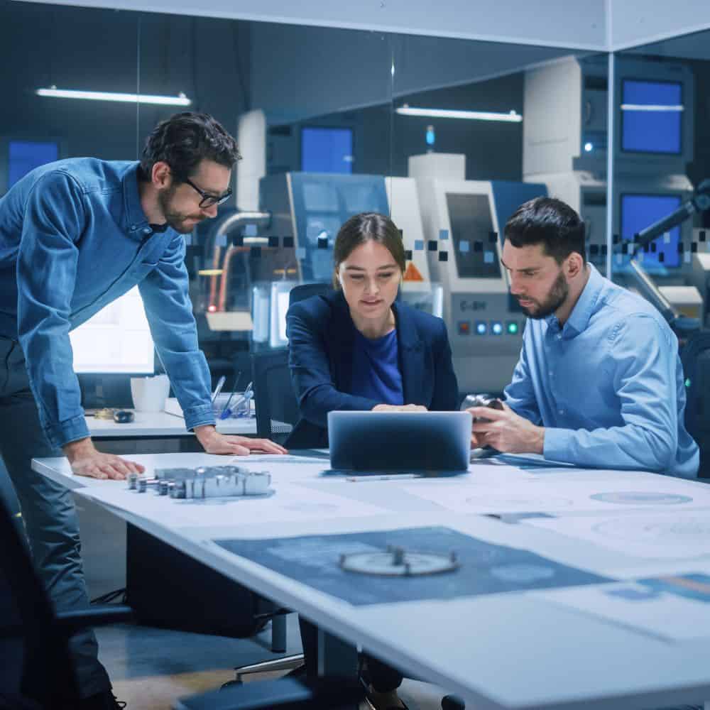 Workers in technology sat round a table in a futuristic office