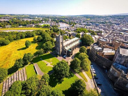 Image of a town in the UK with green fields, a church and buildings in the background