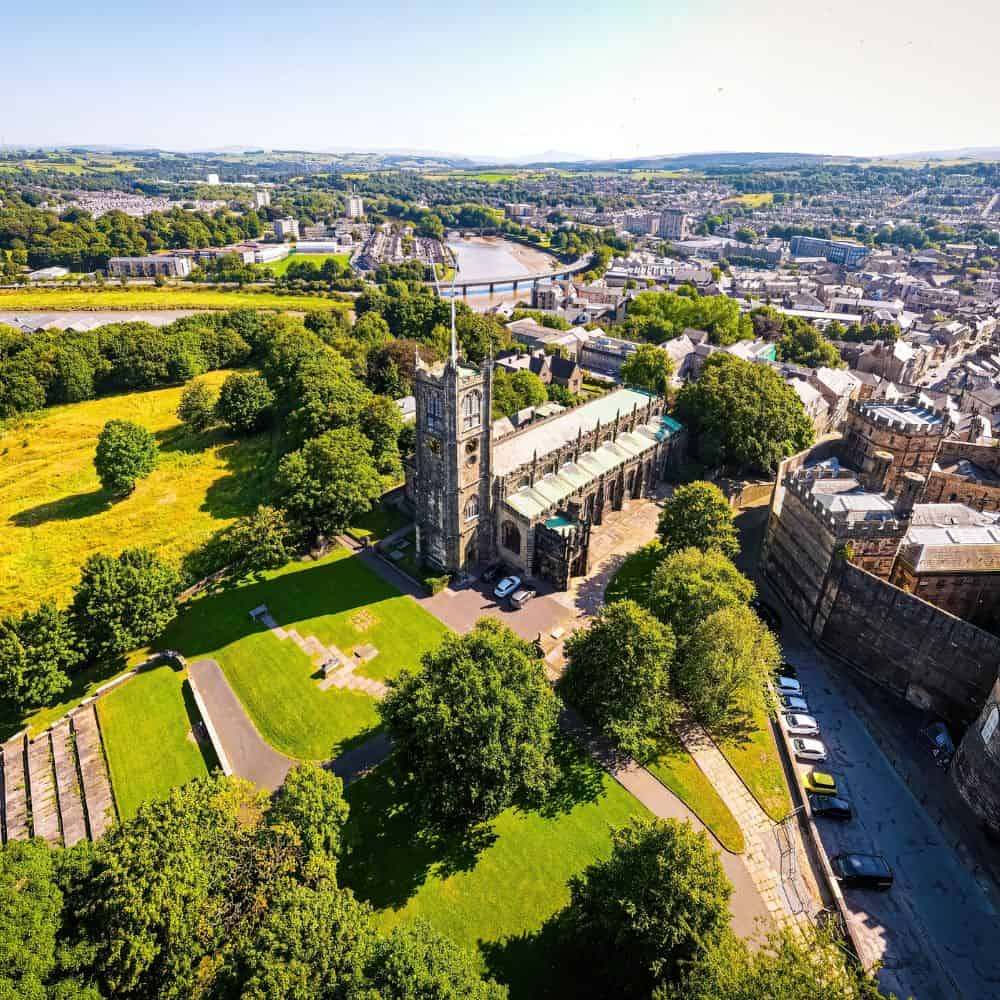 Image of a town in the UK with green fields, a church and buildings in the background