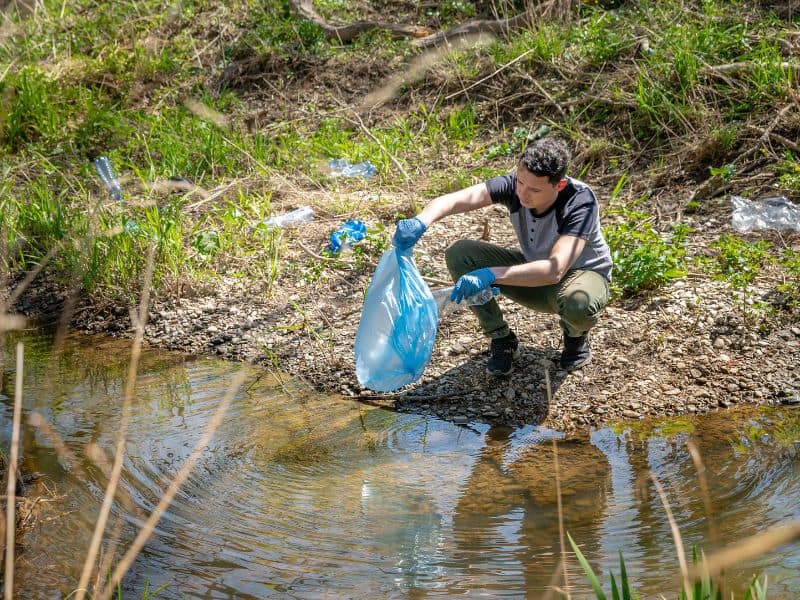 Photo of man clearing plastic waste from a river