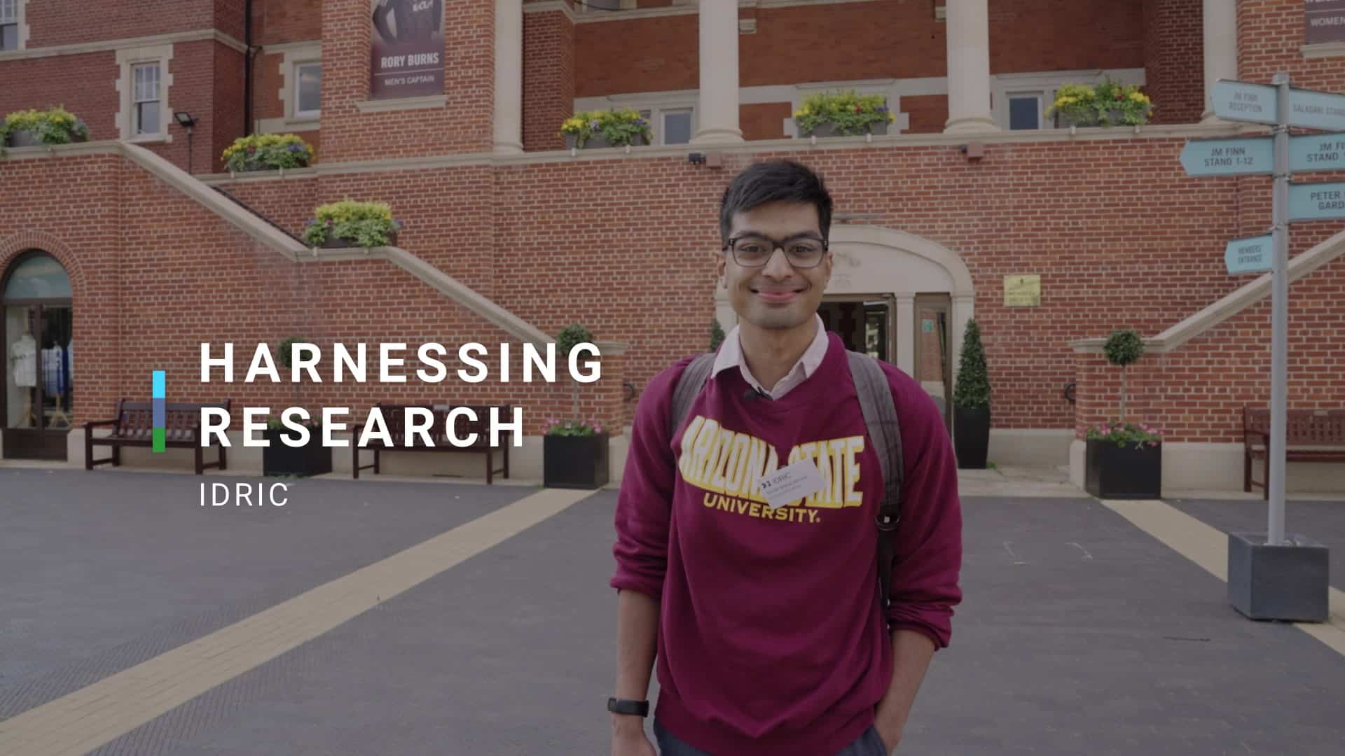 IDRIC video thumbnail. Male standing outside in front of a red-brick building.