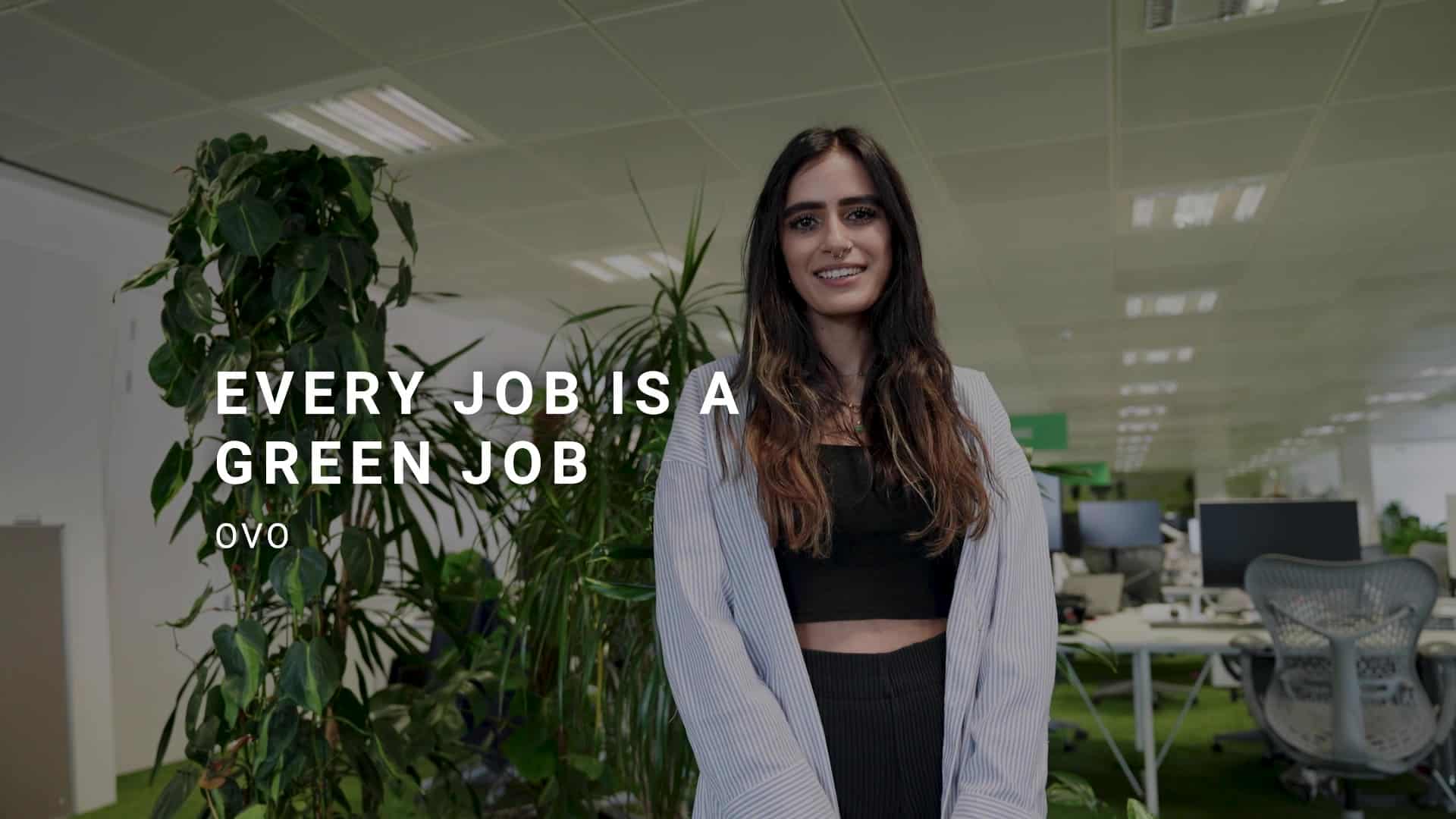 OVO Group video thumbnail. Young woman in an office next to a large plant.