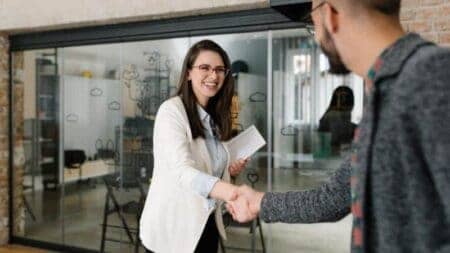 A woman and a man greeting with a handshake