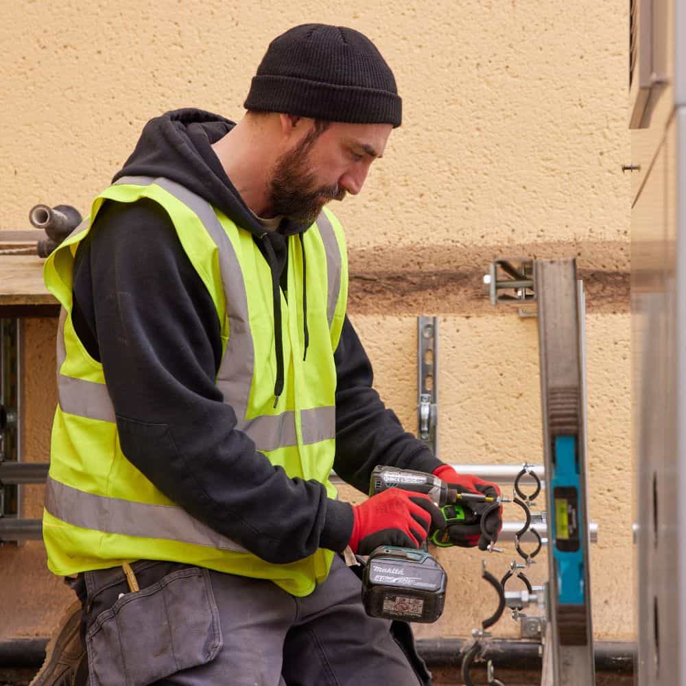 Man in high-vis jacket installing a heat pump
