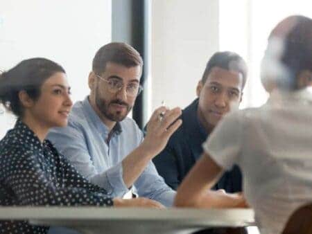 3 people interviewing a woman, all sitting at a table