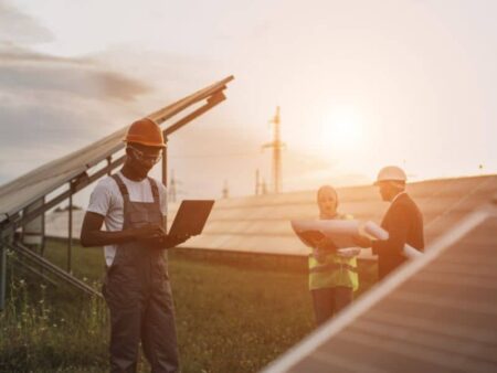 Three people with clipboards in a solar farm field