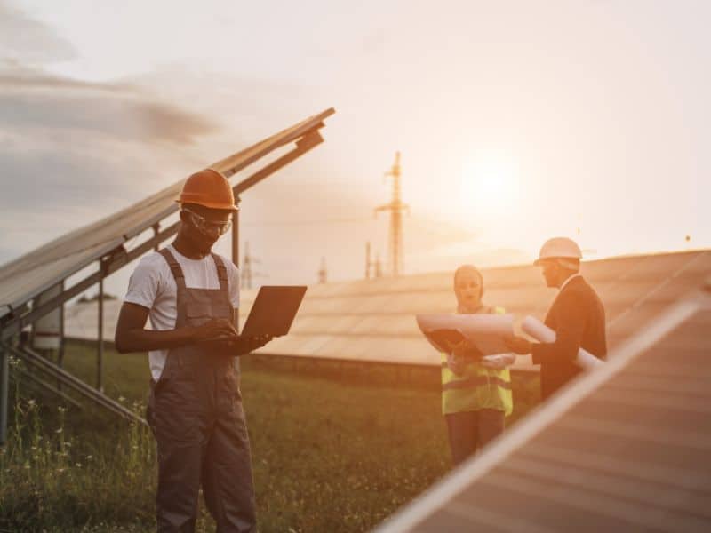 Three people with clipboards in a solar farm field