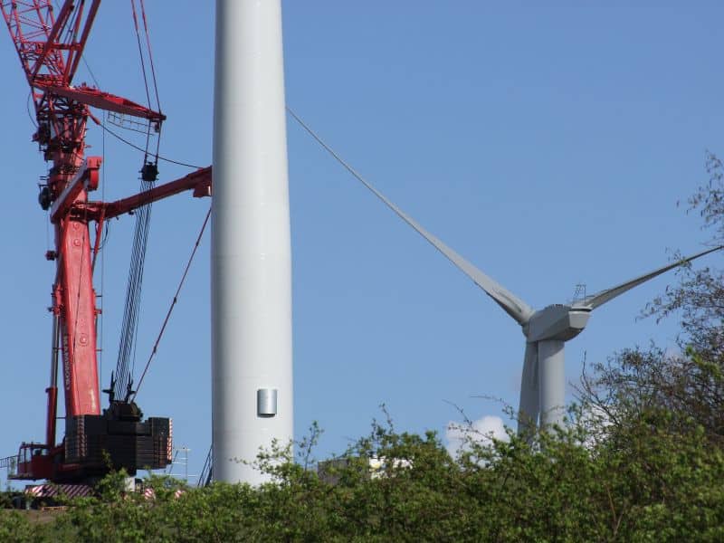 Photo of a wind turbine up close, next to a crane