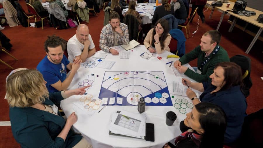 Image of students sitting around a round table engaged with the game