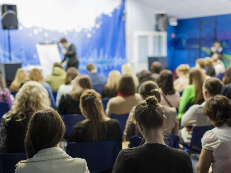 Photo of someone presenting on a stage in front of an audience