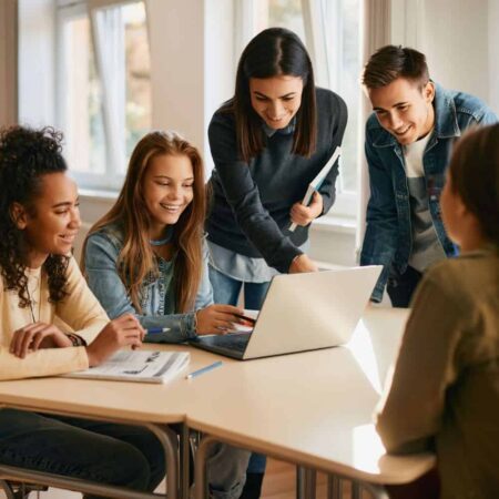 Teacher showing young students something on a laptop