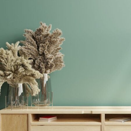 Plants in a vase against a green wallpaper background