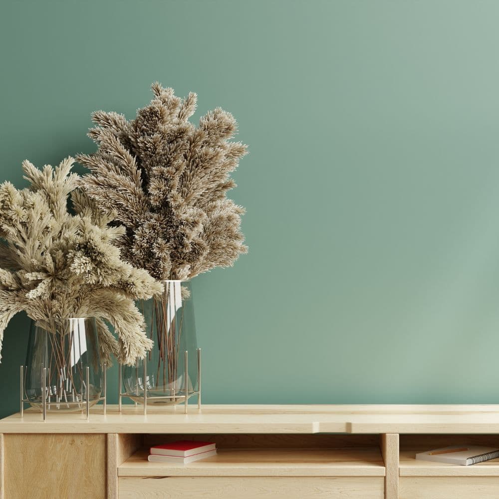 Plants in a vase against a green wallpaper background