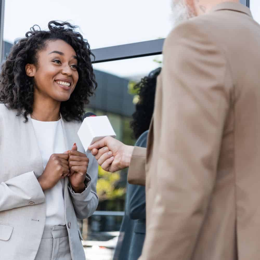 Photo of woman being interviewed with a microphone outside a building