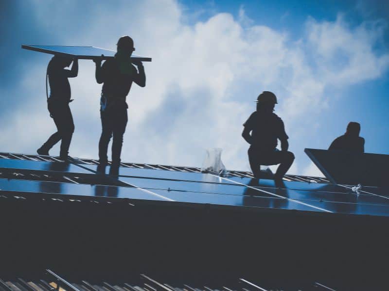 Photo of four people installing solar panels on a roof