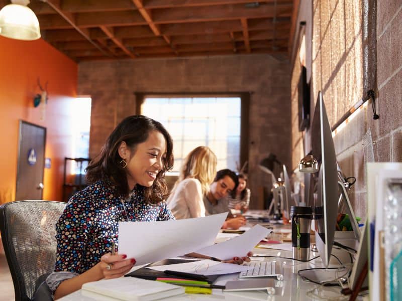 Image of 3 young people working at computers with papers in front of them