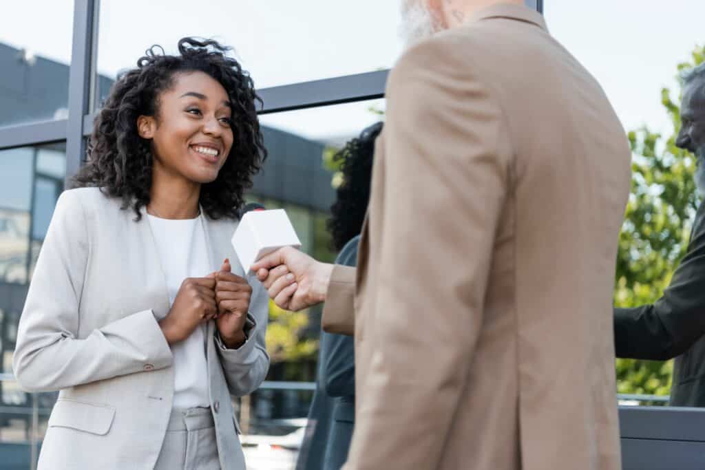 Photo of a woman being interviewed by somebody else, with a microphone being held in front of her