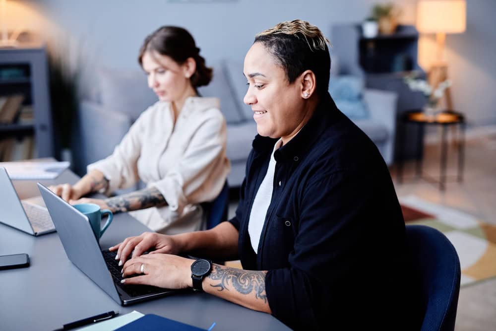 Two people at a desk working on laptops