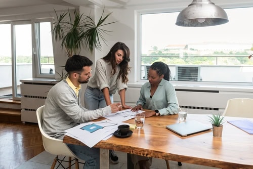 Three people at a large table looking at building plans
