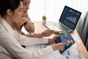 Two people in an office looking at data and graphs on two devices