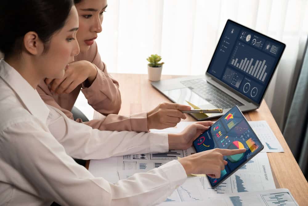 Two people in an office looking at data and graphs on two devices