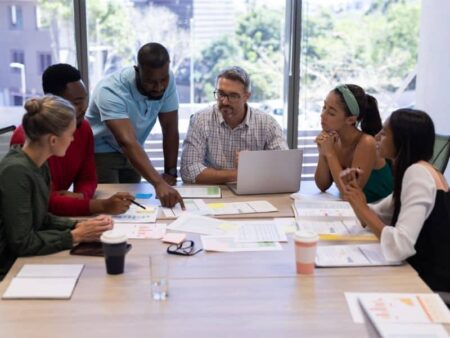 group of people in an office working around a meeting room table