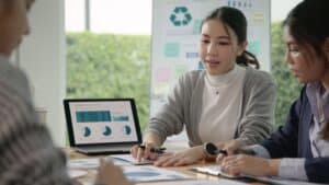 woman speaking to colleagues and showing them graphs on a computer screen