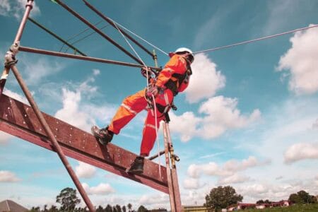Image of person on a building structure - they are wearing a hard hat and high visibility vest