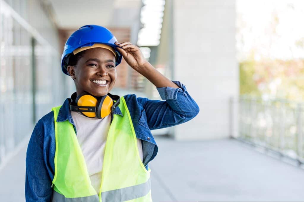 Woman smiling at the camera, wearing a high-vis jacket and a blue hard hat