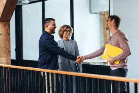 Three people - interviewee shaking the hands of someone else