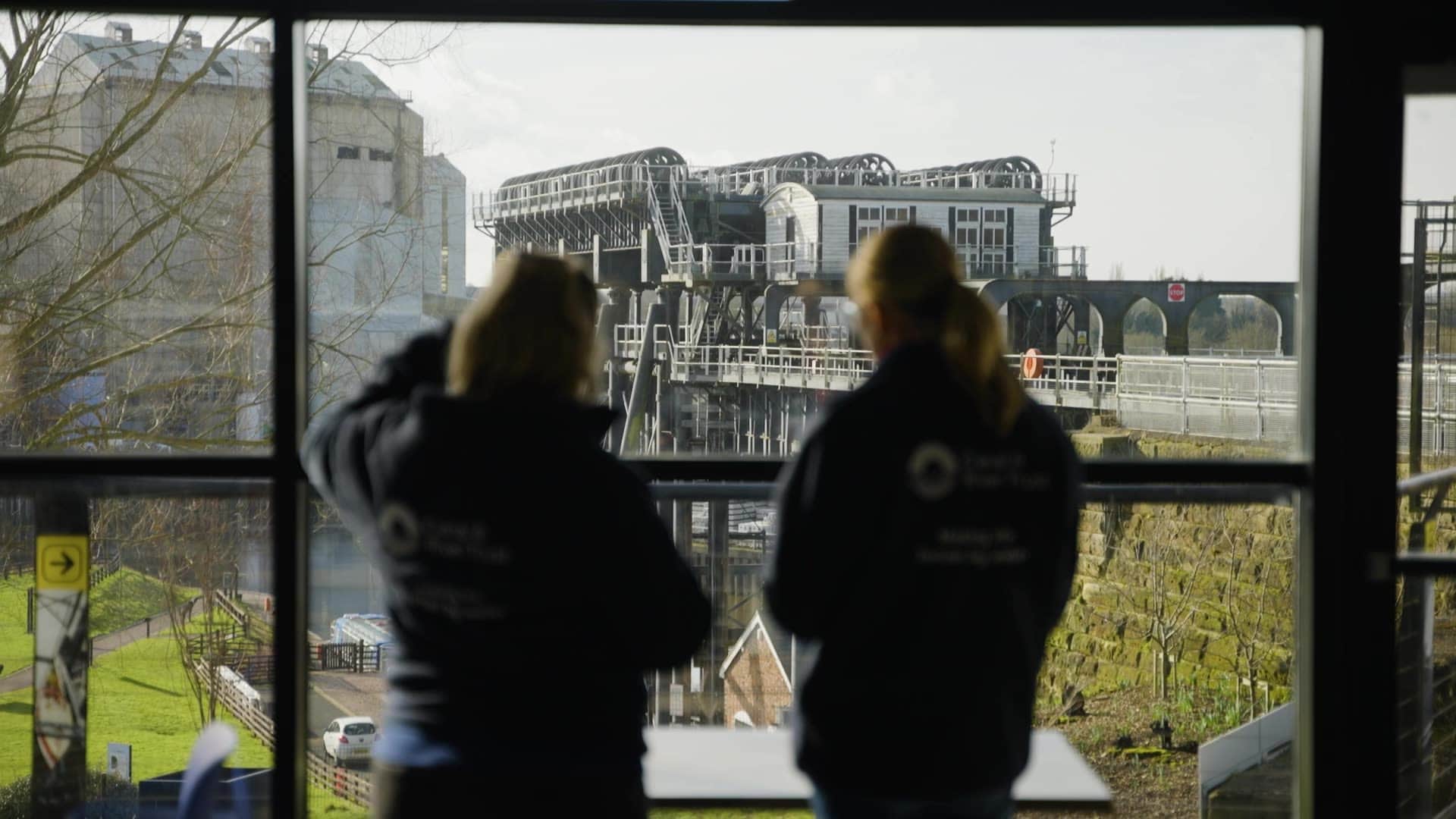 Frame from the video of two people looking at a canal
