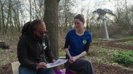 Two people sat on a bench looking at a piece of paper
