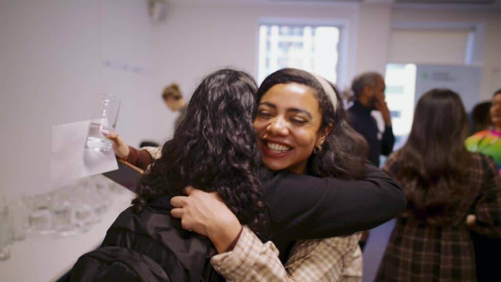 Photo of two people of colour smiling and hugging