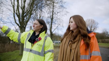 Two people walking through an industrial site and talking